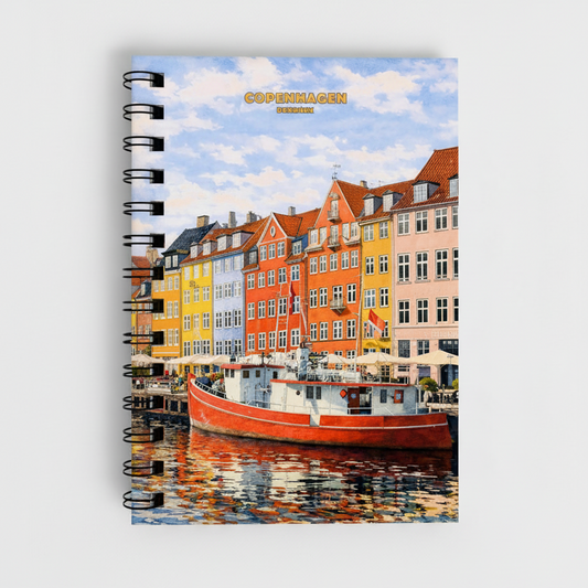 A spiral-bound notebook featuring a colorful printed illustration of Copenhagen's Nyhavn canal with buildings, boats, and reflections, shown on a light gray background.