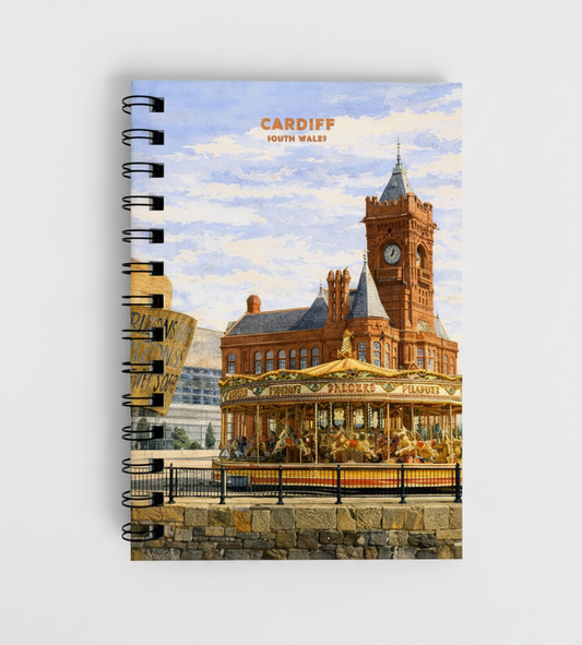 A spiral-bound notebook featuring a vintage-style painted illustration of Cardiff, South Wales, with the clock tower and carousel visible on the cover, shown against a light gray background.
