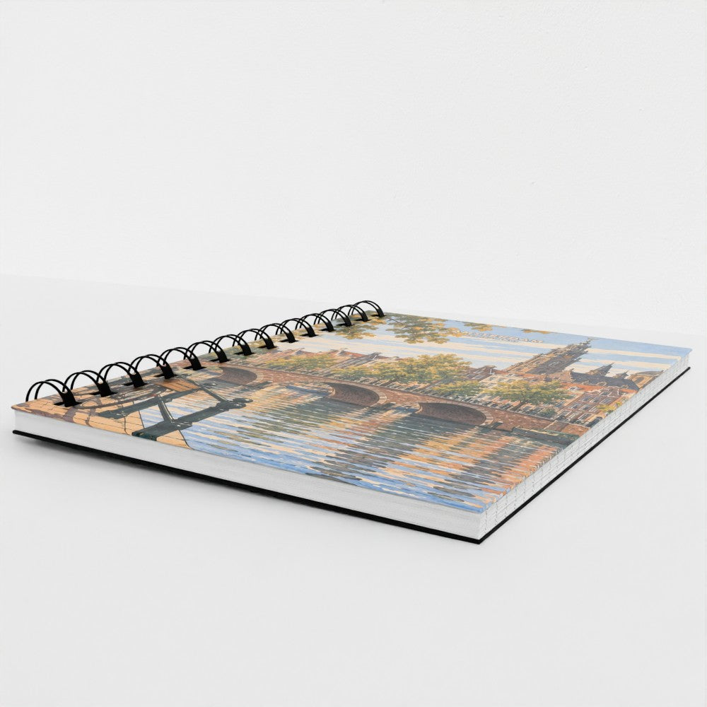 A spiral-bound notebook with a scenic city bridge and water reflection cover, photographed on a clean white background.