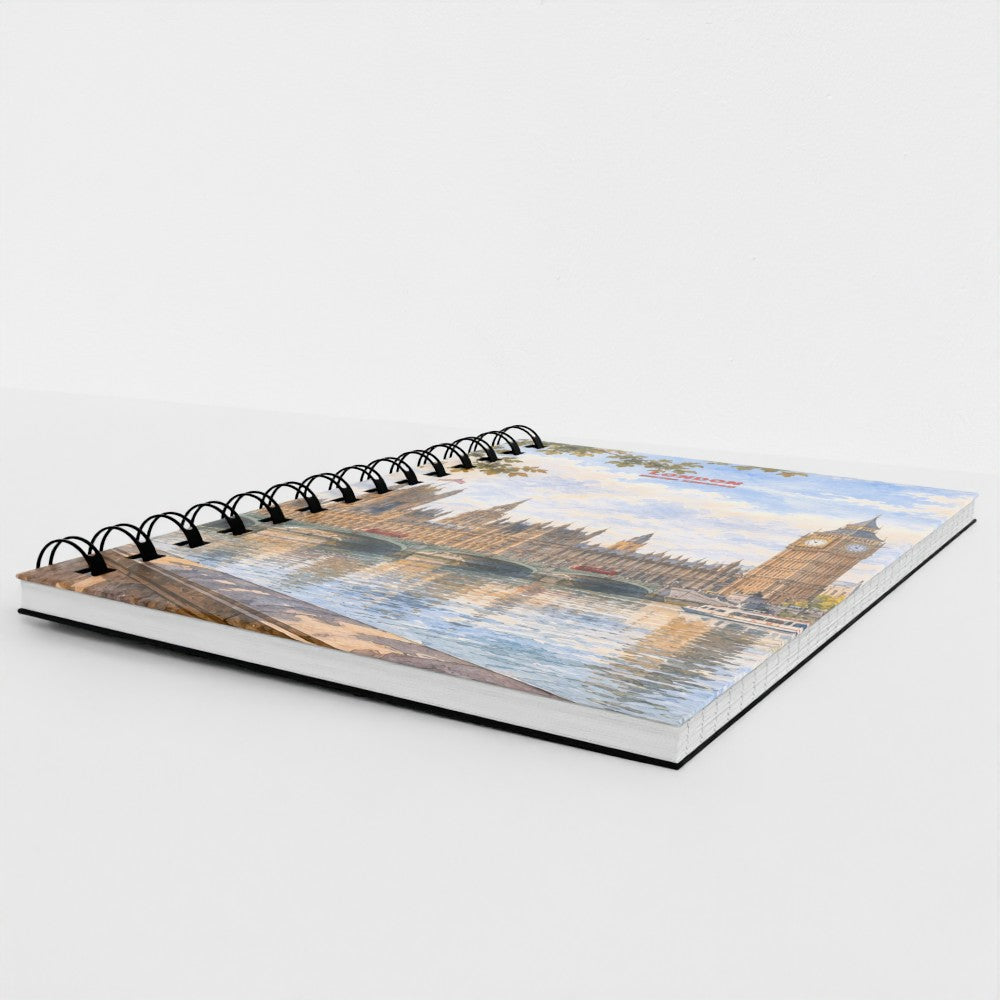 A spiral-bound notebook featuring a scenic print of Big Ben and the London Eye reflected in the water, photographed on a clean white background.