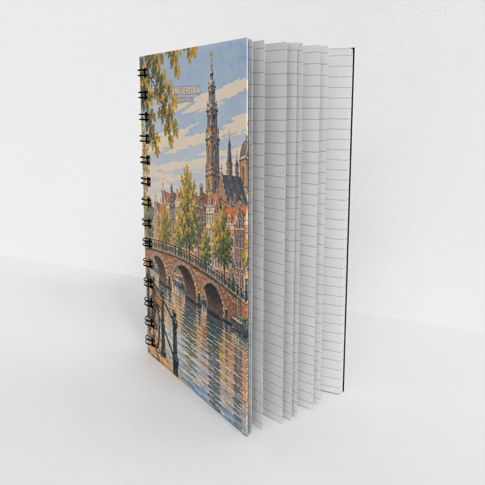 A spiral-bound notebook standing upright on a light gray surface. The cover features a colorful illustration of a canal-side city scene with buildings, a bridge, trees, and water.