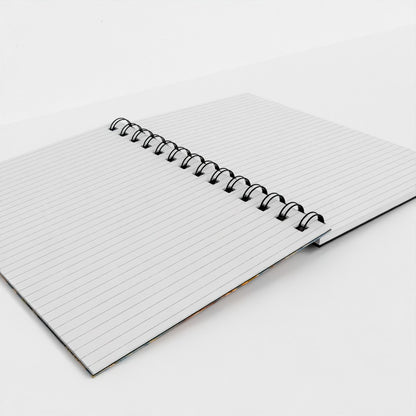A white ruled spiral notebook with a black metal coil binding, shown open on a clean white background.